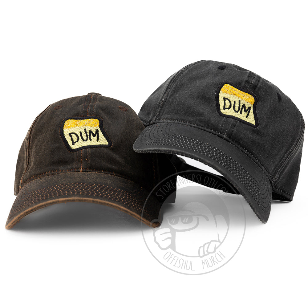  A photograph of the Black & Brown DUM baseball hats designed by Puffballs United on a white background. The black DUM hat sits askew overlapping the brown DUM hat on the left.