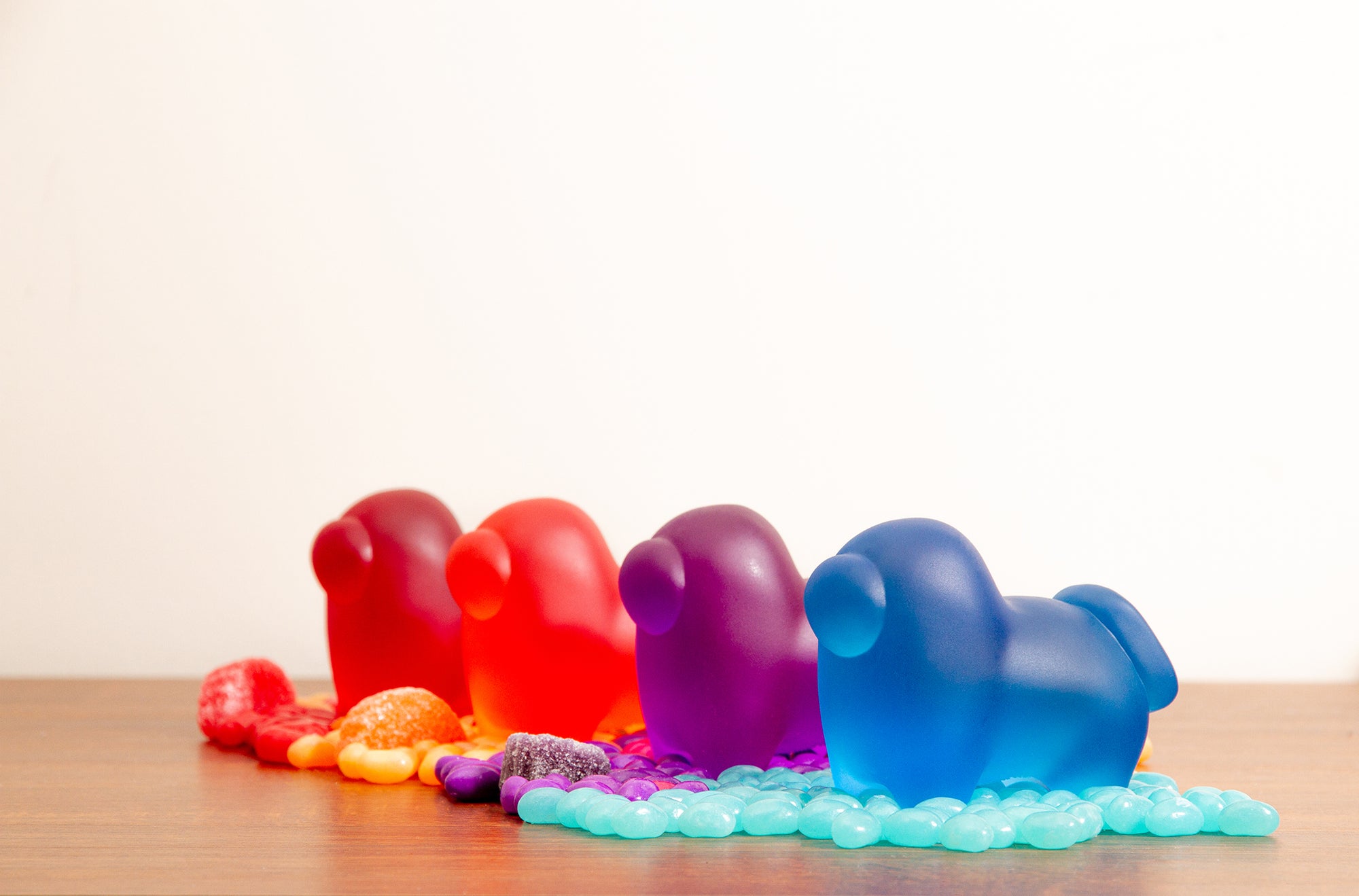 A diagonal shot of the Four Horse-shaped Crewmate figurines, red, orange, purple, and blue, standing on top of jellybeans that match their respective colors.