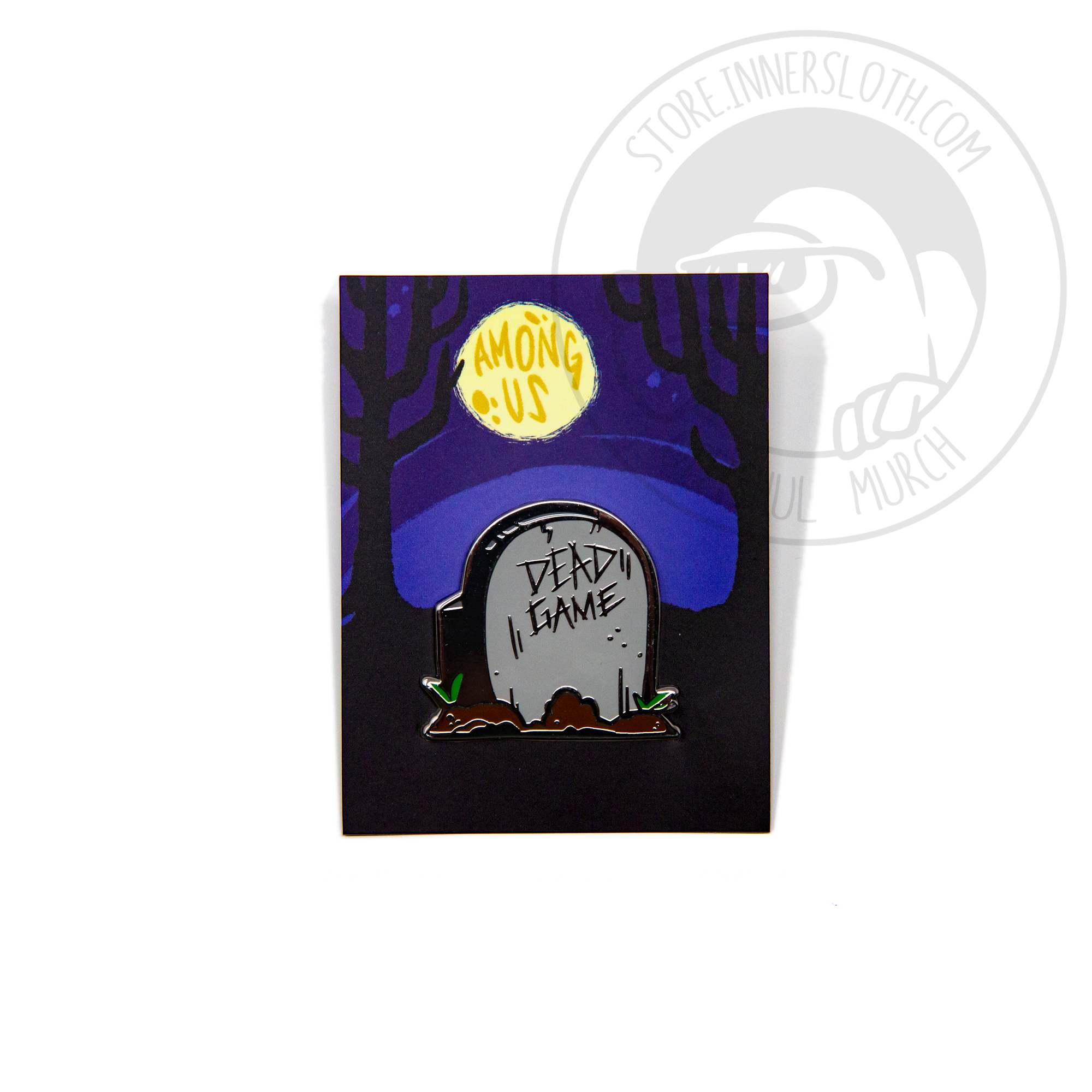 A product photo of a hard enamel pin depicting a grey headstone surrounded by small mounds of fresh dirt and grass sprouts. The headstone is vaguely crewmate-shaped, and reads “DEAD GAME.”