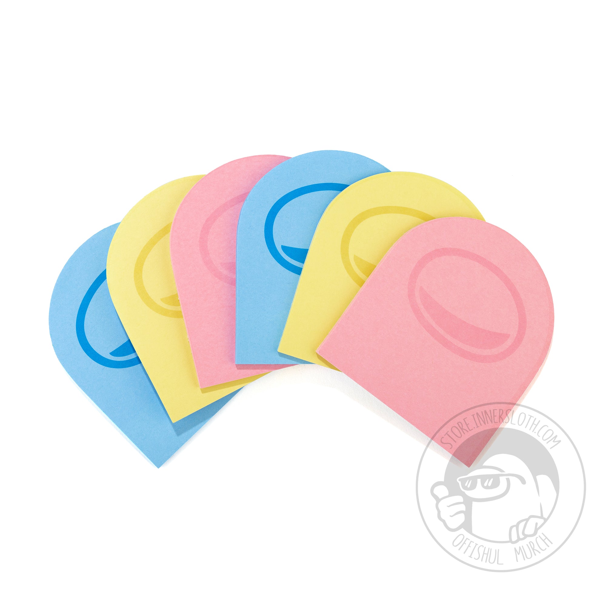 A product photo of six packs of Post-It notes, shaped like crewmate heads. Two of each of the Post-It colors are shown: blue, yellow, and pink. A faded visor design are printed on all the Post-Its. The Post-It notes are spread across a surface in an arc like a deck of cards.