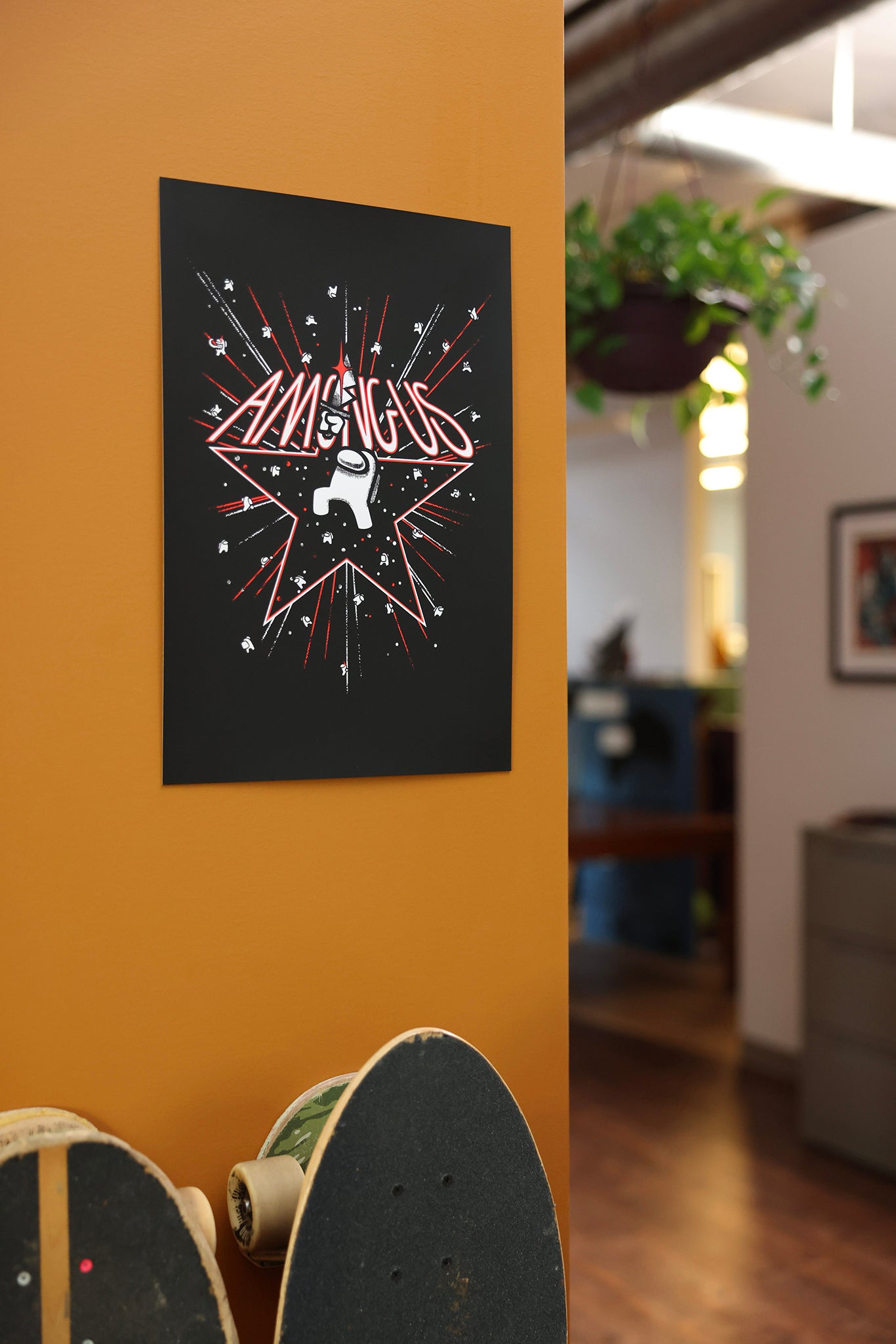 A close up photograph of a model’s hands holding up the Among Us: 5th Anniversary Print  by Amy Liu. The print depicts a white Impostor among a flurry of stars and fireworks. The impostor stands in the middle of a red outlined star holding a bloody knife over their head. “Among Us” text is written in red and white sitting on top of the outlined star. 