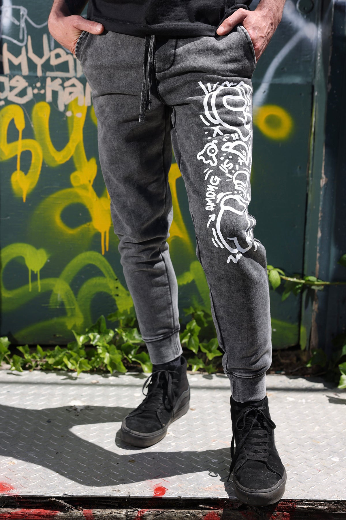 A ¾, half body, photograph of a model wearing textured gray joggers with the Crewmate patterned motif. 
