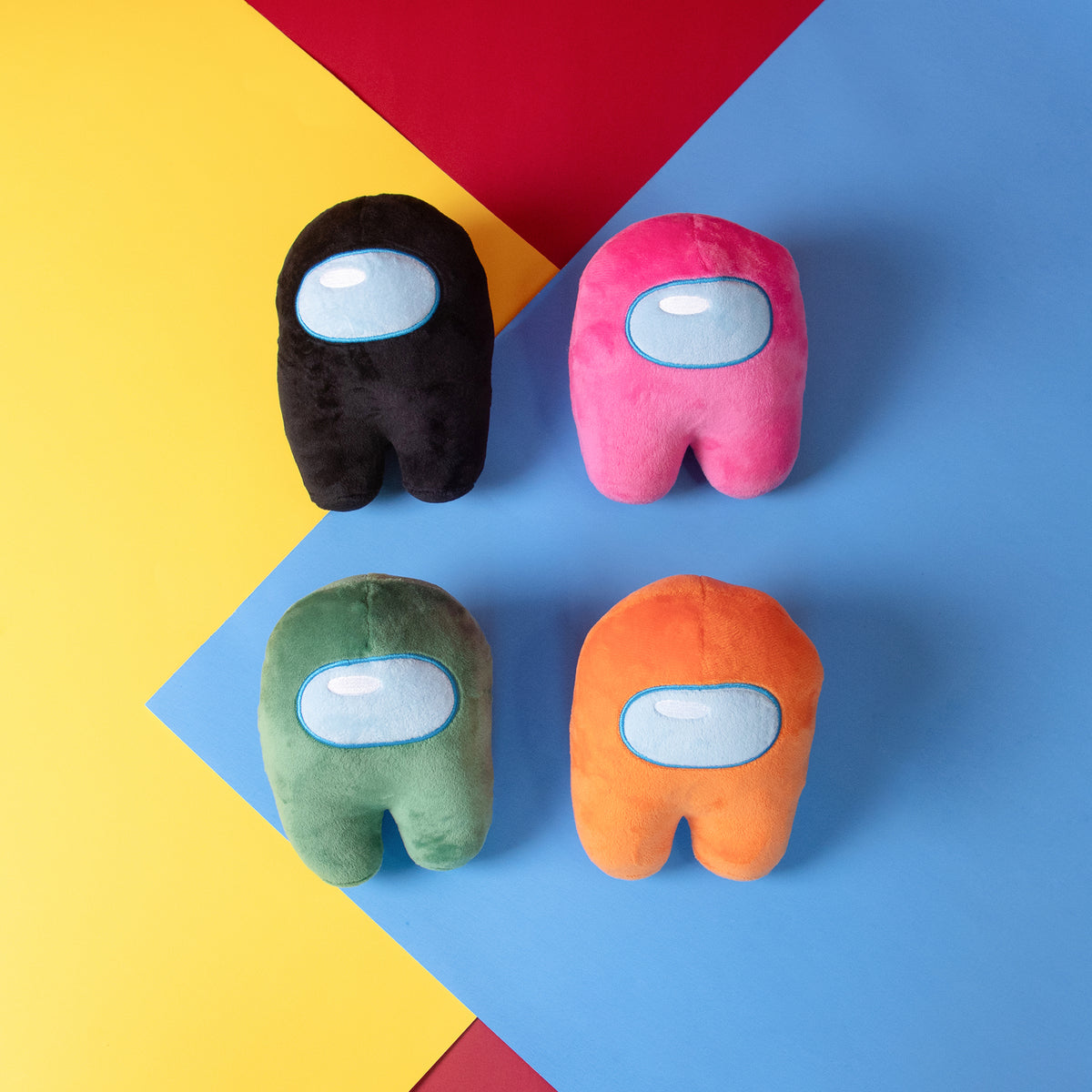 Lifestyle Photograph of a Black, Green, Orange, and Pink Crewmate Plush by Frisk Wolfie stacked in two rows of two against a yellow, red, blue color blocked background.
