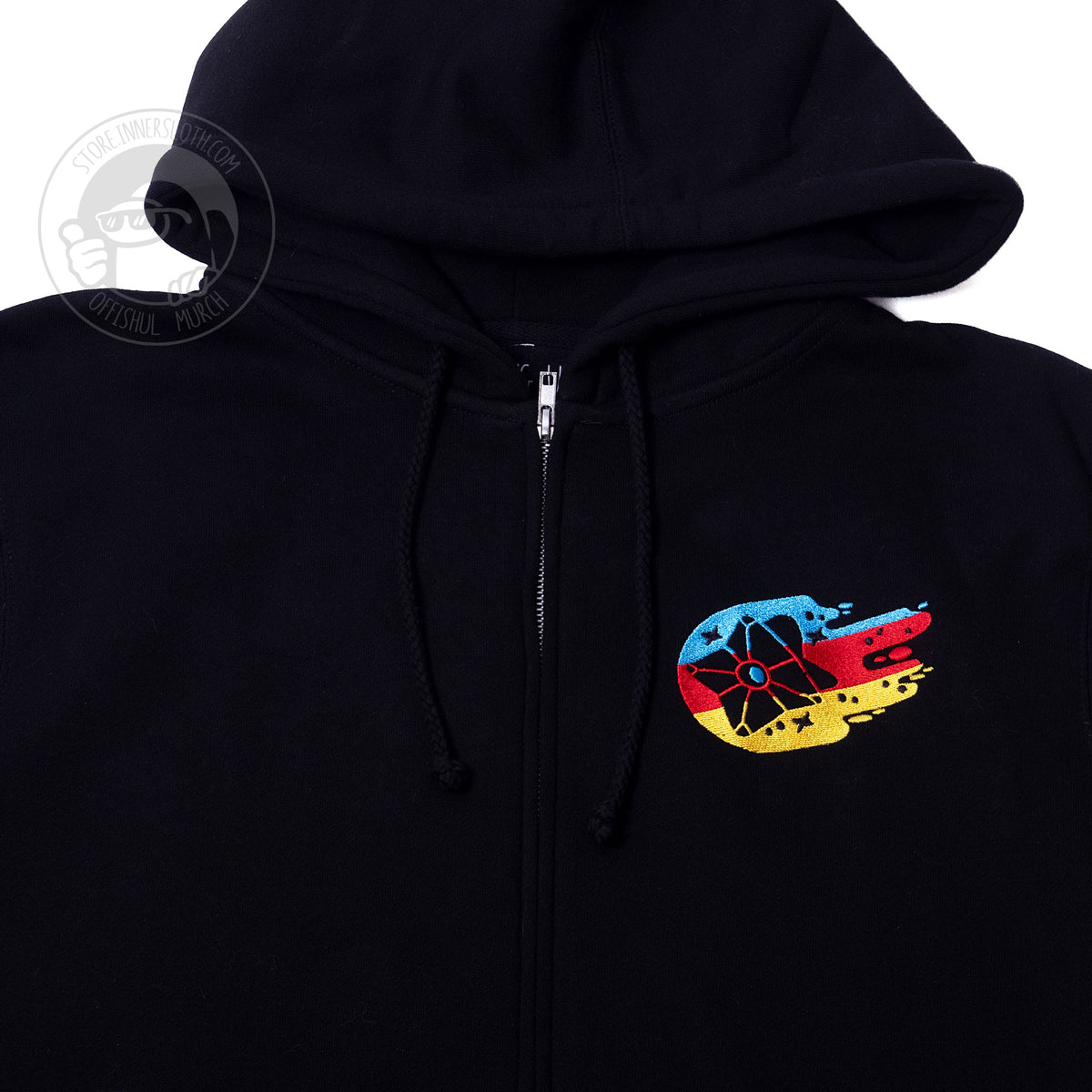 A close up photo of the front of the hoodie, showing off the left side embroidery chest hit. The embroidery is a tetrahedral shaped Ghost machine surrounded by multi-colored streaks of blue, red, and yellow. There are stars and tiny dots sprinkled in between the colored streaks. 
