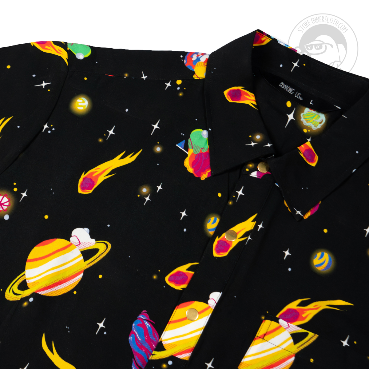 A close crop of the top left of a black short-sleeved button-up shirt on a white backgroud. The black button-up is covered in crewmates from Among Us, as well as meteors, shooting stars, and planets.
