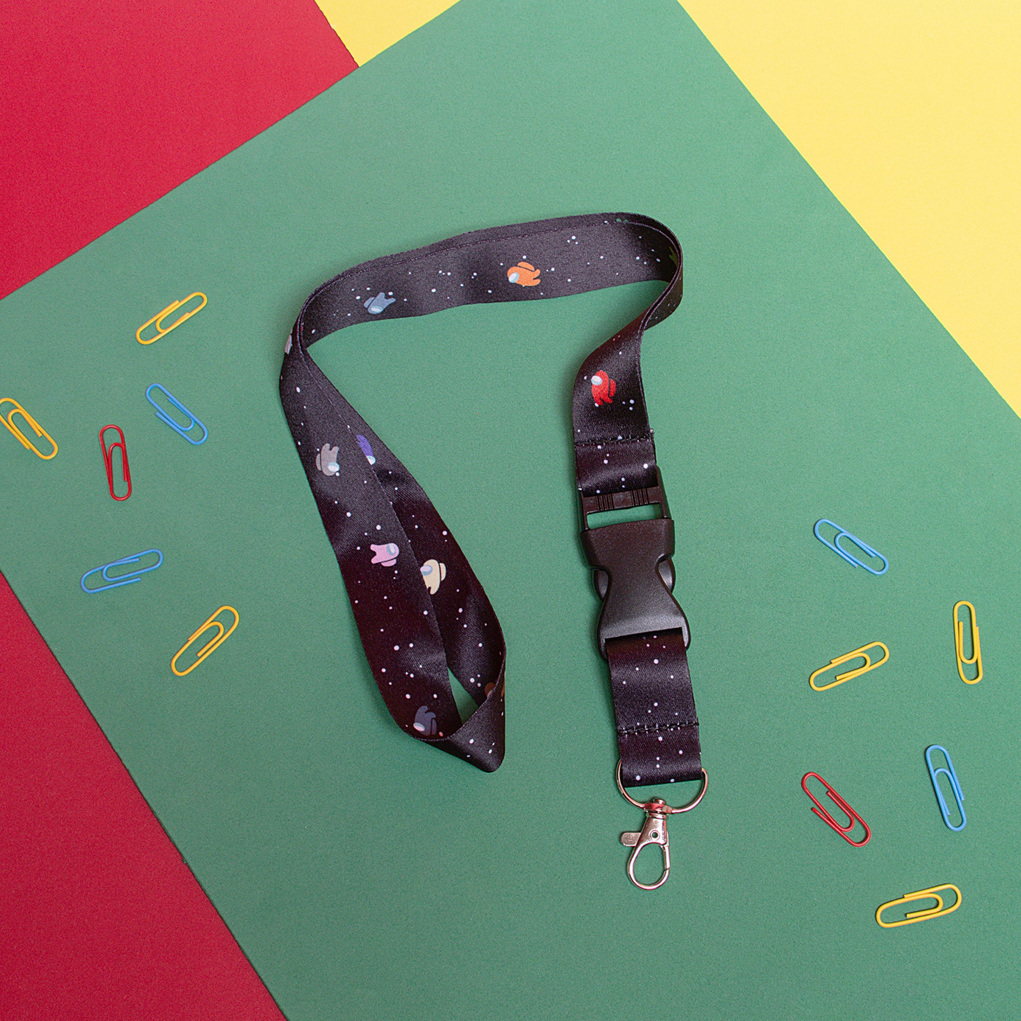 A black lanyard with a Space background, with multicolored Among Us Crewmates on it.