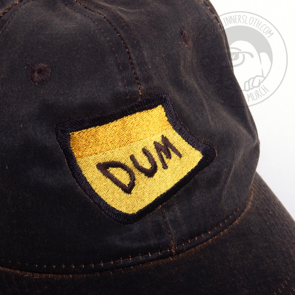 A close up photo of the Brown DUM hat showing the DUM embroidery detail.