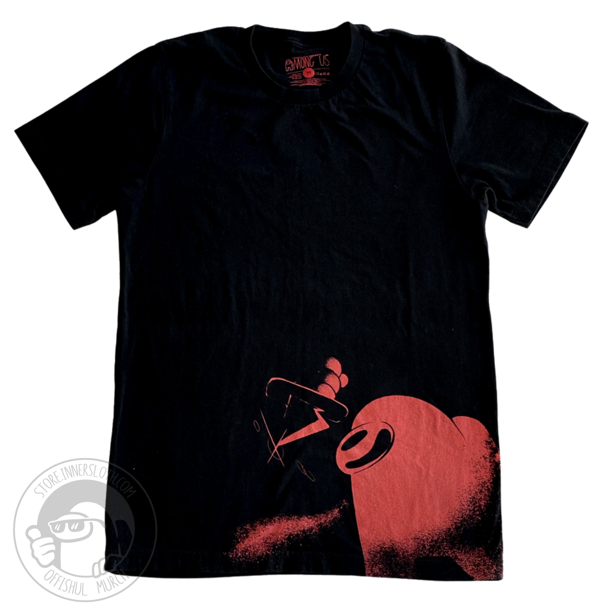 A flat lay photograph of a black t-shirt with a stylized red crewmate holding a dagger at the bottom right corner. The art is stylized to look spray painted.