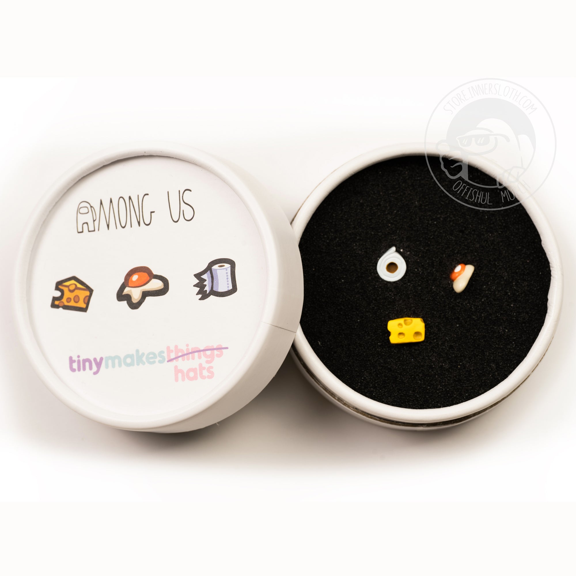 A product photo from above of the white container the keycaps come in. The top of the cardboard cylinder shows illustrations of each of the hats. The container is open, showing the fried egg, cheese wedge, and toilet paper on a black spongey material.