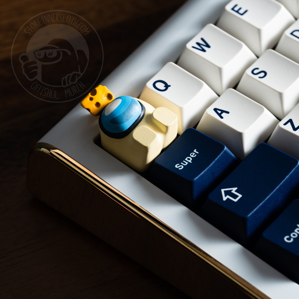 A dramatically lit lifestyle photo of the banana crewmate keycap taking the place of the escape key on a luxe white keyboard. The crewmate keycap figure lays on its back, and is shown with a cheese wedge atop its head.