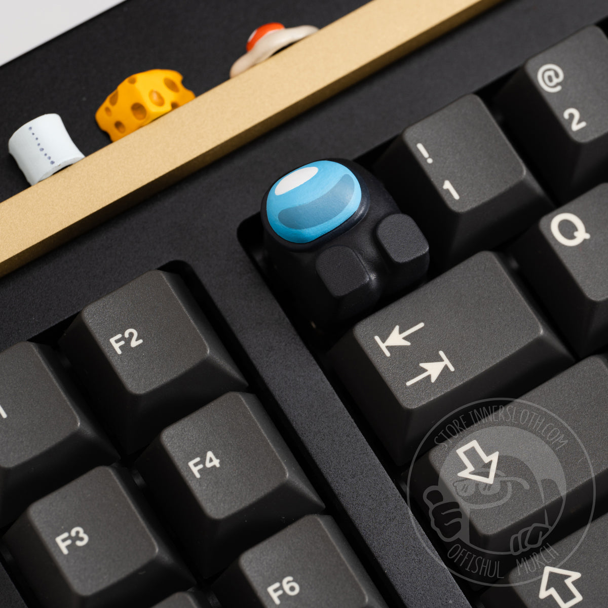 A product photo of the cyan keycap taking the place of the escape key on a black keyboard. 