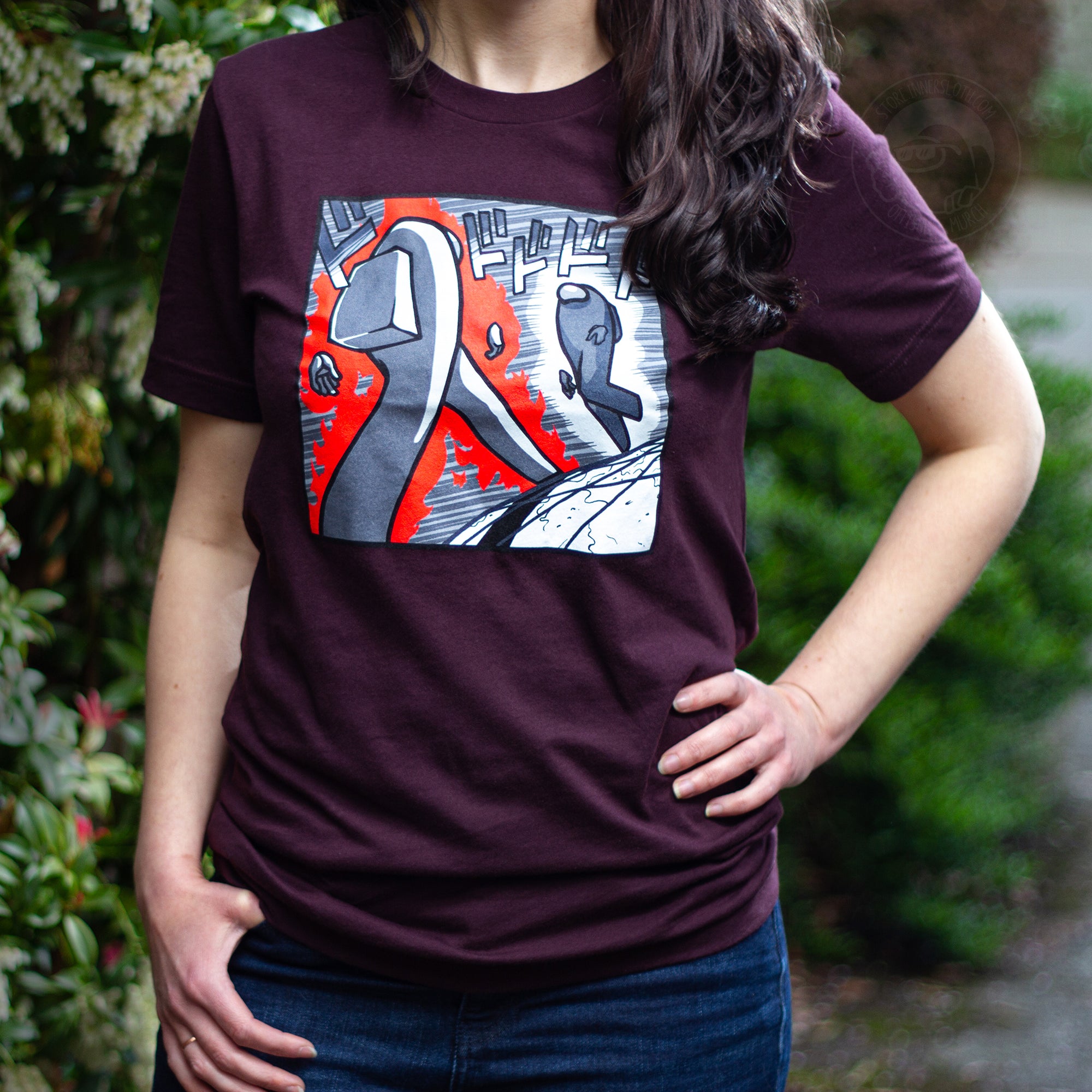  A flat lay photograph of the Among Us: Menacing T-Shirt. The maroon shirt depicts one long-legged crewmate striding to another, replicating the iconic scene from JoJo's Bizarre Adventure.
