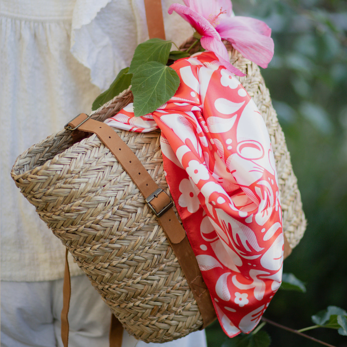 A lifestyle photograph of the scarf hanging out of a woven purse.
