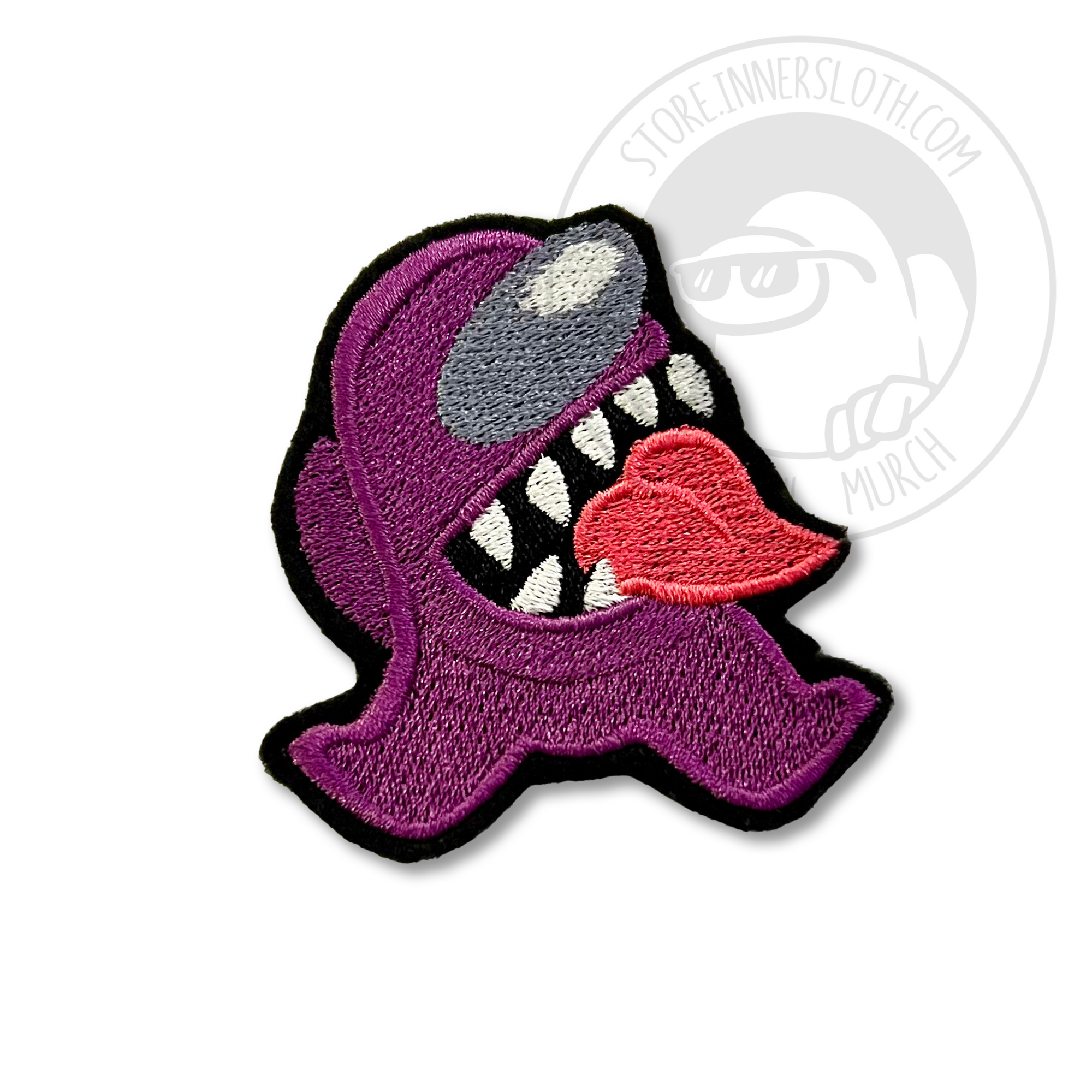 A product photo of a stylized purple Imposter patch, with grinning sharp teeth and a red tongue. Its legs splay out to the sides.