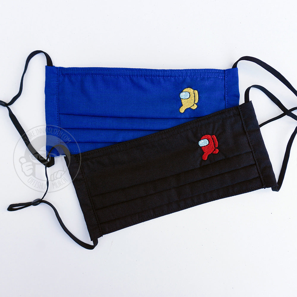 A flat lay photo of two cloth mask covers laying over one another. The top mask is blue with an embroidered running yellow crewmate in the upper left quadrant of the mask.. The bottom mask is black with a small embroidered running red crewmate in the upper left quadrant of the mask.Both masks have black, adjustable ear loops.