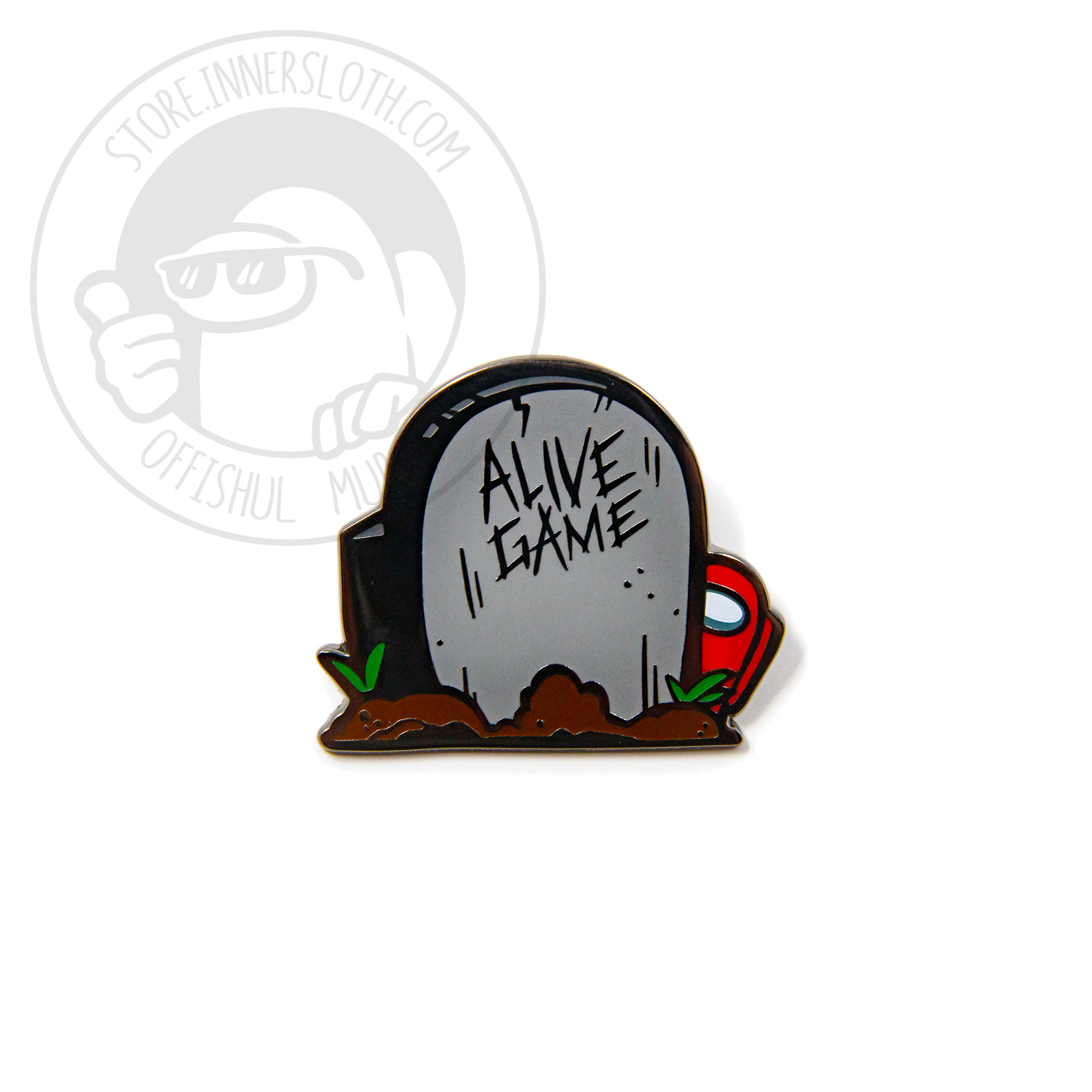 A product photo of a hard enamel pin depicting a grey headstone surrounded by small mounds of fresh dirt and grass sprouts. The headstone is vaguely crewmate-shaped, and reads “ALIVE GAME.” A small red crewmate peeks out from behind the headstone.