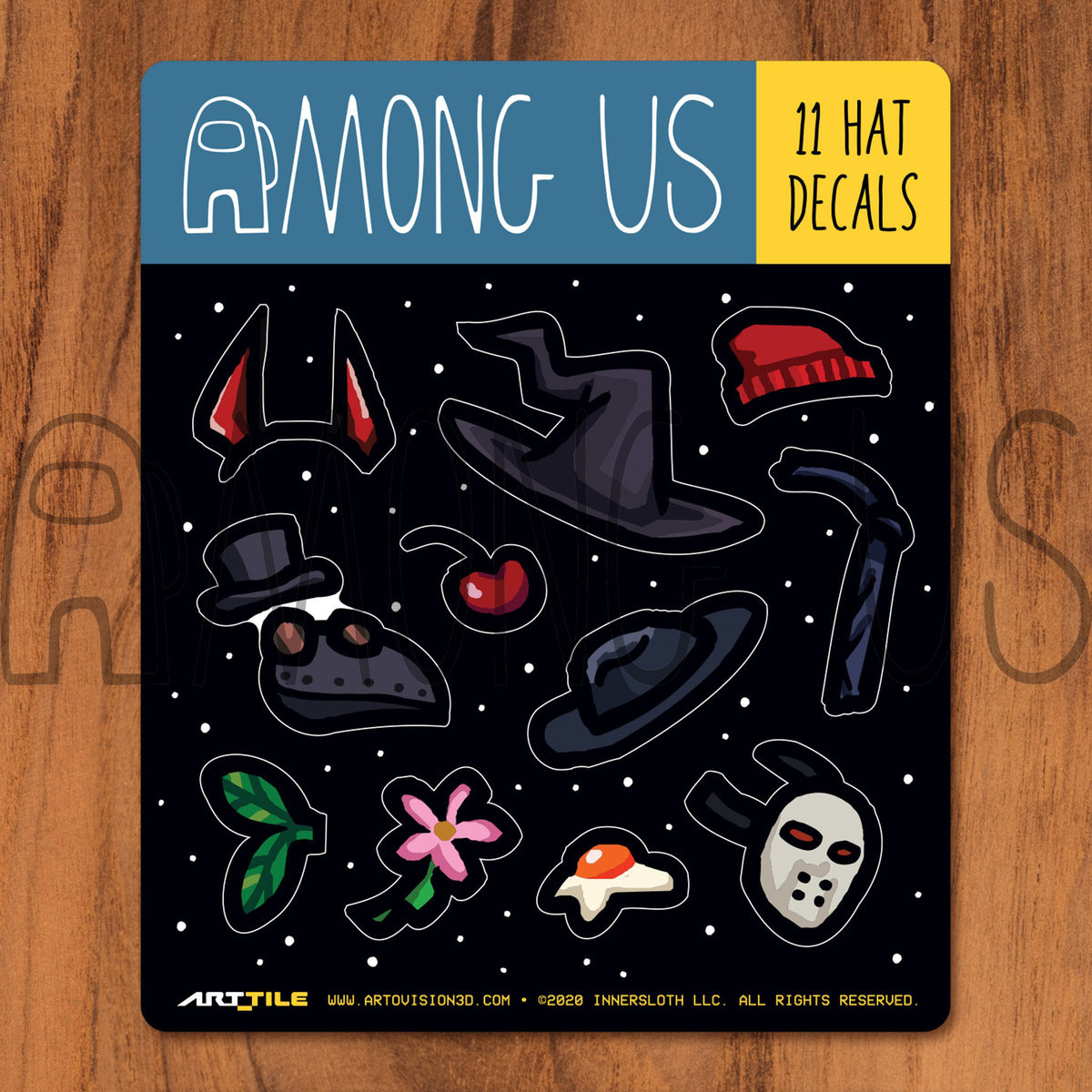 A product photograph of the hat decals that are part of the Among Us: Crewmate Art Tile Decals by Artovision3D. There are 11 hat options on the sheet: Imp-ressive horns, red beanie, cherry, egg, hockey mask, Daisy Me Rollin’ pink flower, black fedora, black bandana, black witch hat, and plague mask with tophat.