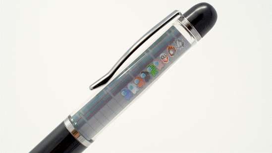 A black plastic floaty pen with a double-sided clear tube with Crewmate artwork by Noble Demons inside it. The front view of the clear tube features a line of Crewmates suspended in the mineral oil liquid.  A hand tilts the pen slowly showing the Crewmates floating to the opposite side. 